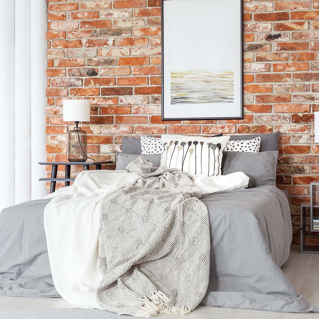 Cozy bed in a guest room with brick wall